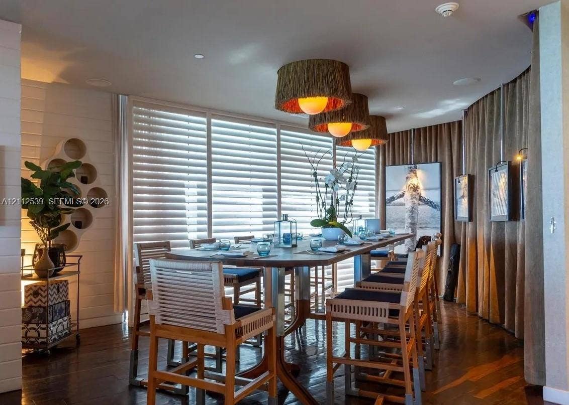 17315 Collins Avenue, #705, Sunny Isles Beach, FL 33160 Wall-mounted circular shelving unit, wood-finish flooring, floor-to-ceiling windows with integrated horizontal blinds, and trio of textured drum pendant lights