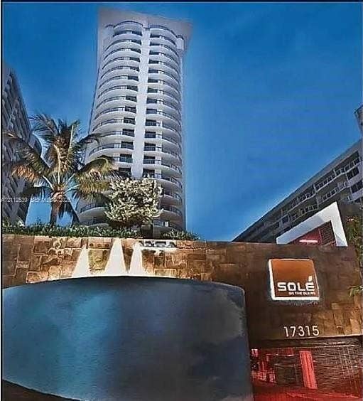 17315 Collins Avenue, #705, Sunny Isles Beach, FL 33160 High-rise residential tower featuring curved balconies, stone-clad masonry wall, and a multi-tiered water fountain