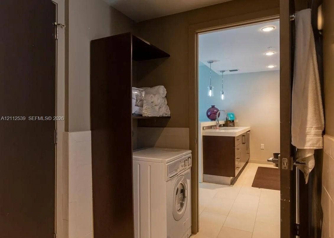 17315 Collins Avenue, #705, Sunny Isles Beach, FL 33160 Laundry area featuring custom floor-to-ceiling built-in cabinetry and tile flooring