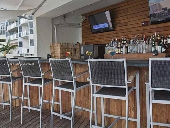 17315 Collins Avenue, #705, Sunny Isles Beach, FL 33160 Outdoor bar featuring wood-plank siding, horizontal wood-slat wall paneling, and a flat-edge stone countertop on a wood-decked patio