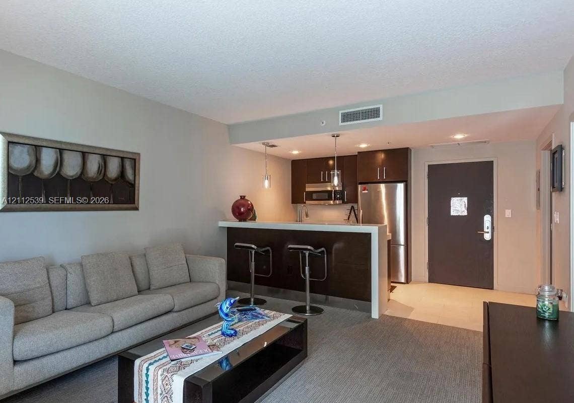 17315 Collins Avenue, #705, Sunny Isles Beach, FL 33160 Kitchen featuring dark wood cabinetry, stainless steel appliances, a breakfast bar with a solid surface countertop, and pendant lighting