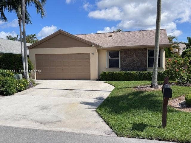 Single-story exterior featuring a stone facade, beige stucco siding, an attached garage, and a concrete driveway
