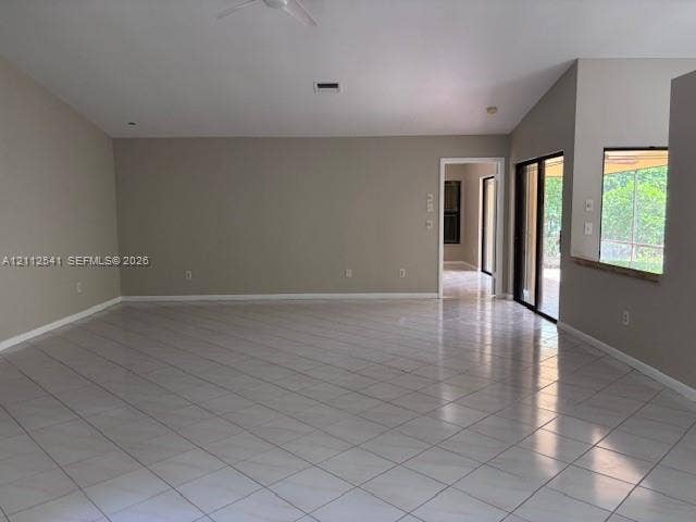 Vaulted ceilings featuring a recessed ceiling fan, neutral wall paint, and ceramic tile flooring throughout, characterized by large sliding glass doors and a wall-cutout serving window