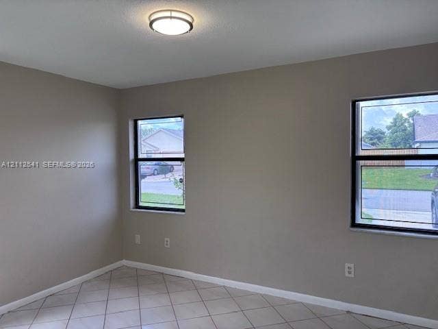 Neutral-toned interior space featuring light-colored tile flooring, flush-mount lighting, and dual windows with black frames