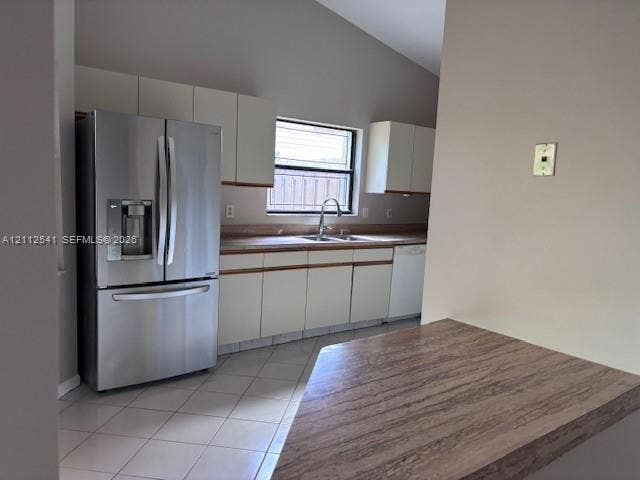 Kitchen featuring white cabinetry, stainless steel French-door refrigerator, laminate countertops, tiled flooring, and vaulted ceilings
