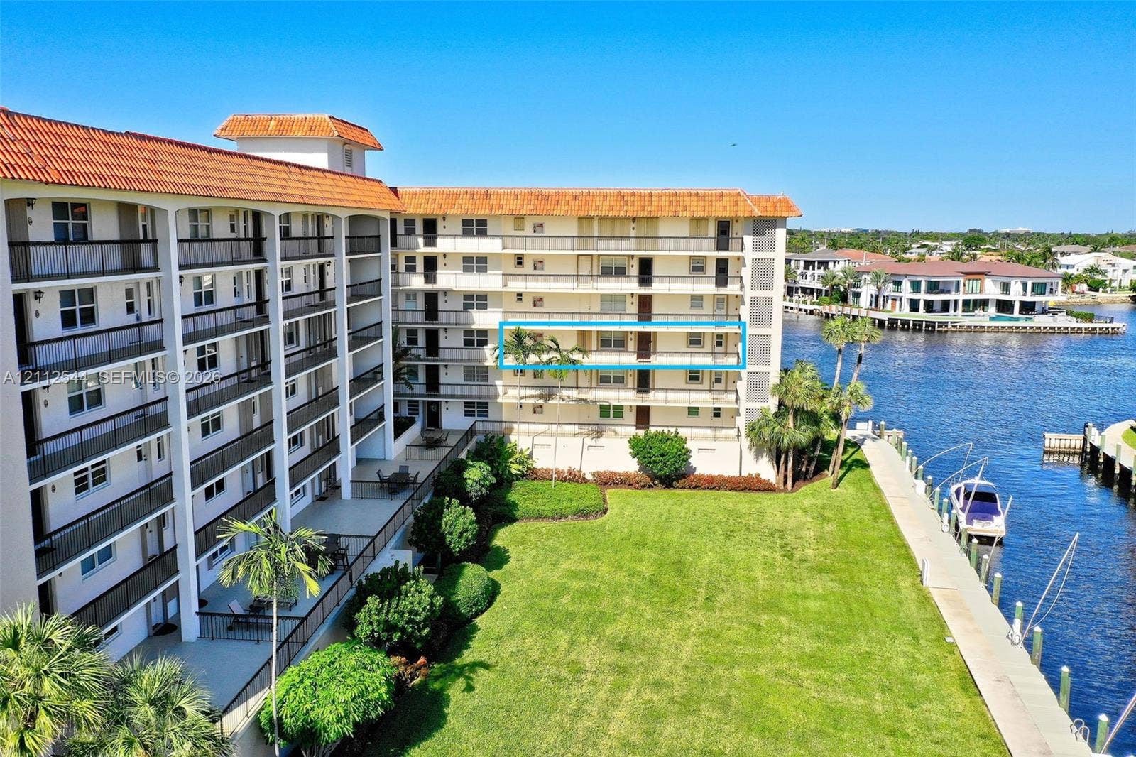 2871 N Ocean Boulevard, #R360, Boca Raton, Boca Raton, FL 33431 Multi-story residential building featuring a terracotta tile roof, private balconies with metal railings, and waterfront grounds with a manicured lawn