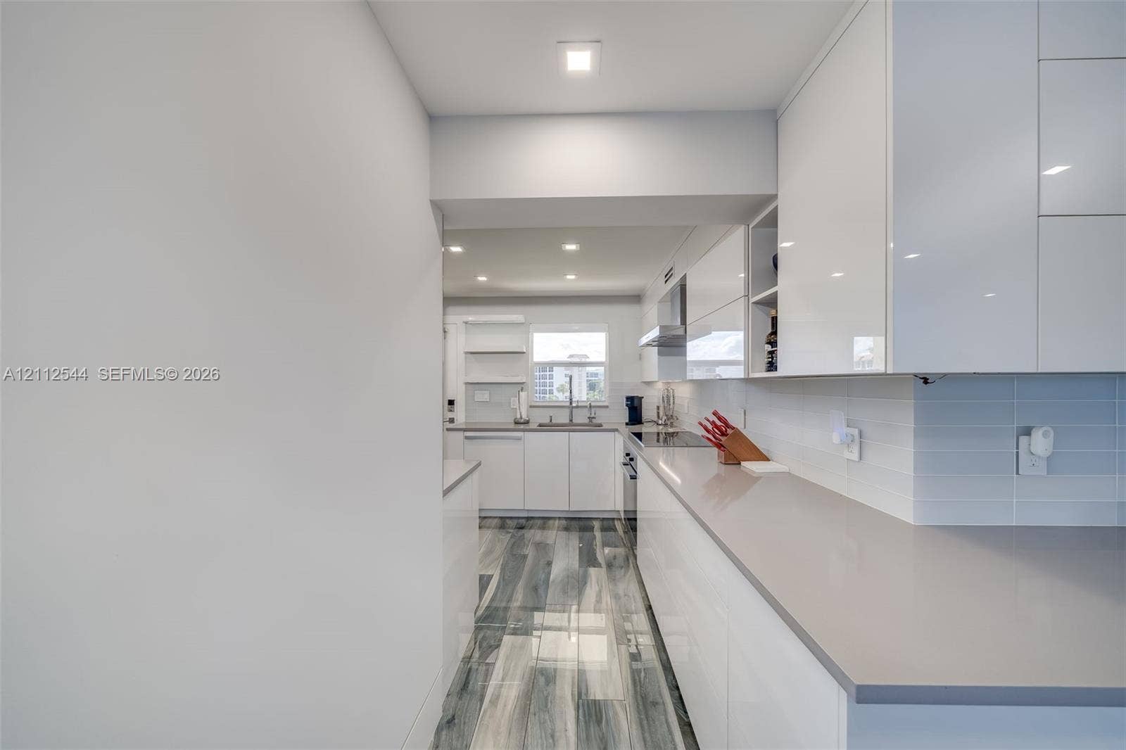 2871 N Ocean Boulevard, #R360, Boca Raton, Boca Raton, FL 33431 Kitchen featuring high-gloss cabinetry, solid-surface countertops, tile backsplash, wood-finish flooring, and recessed ceiling lighting