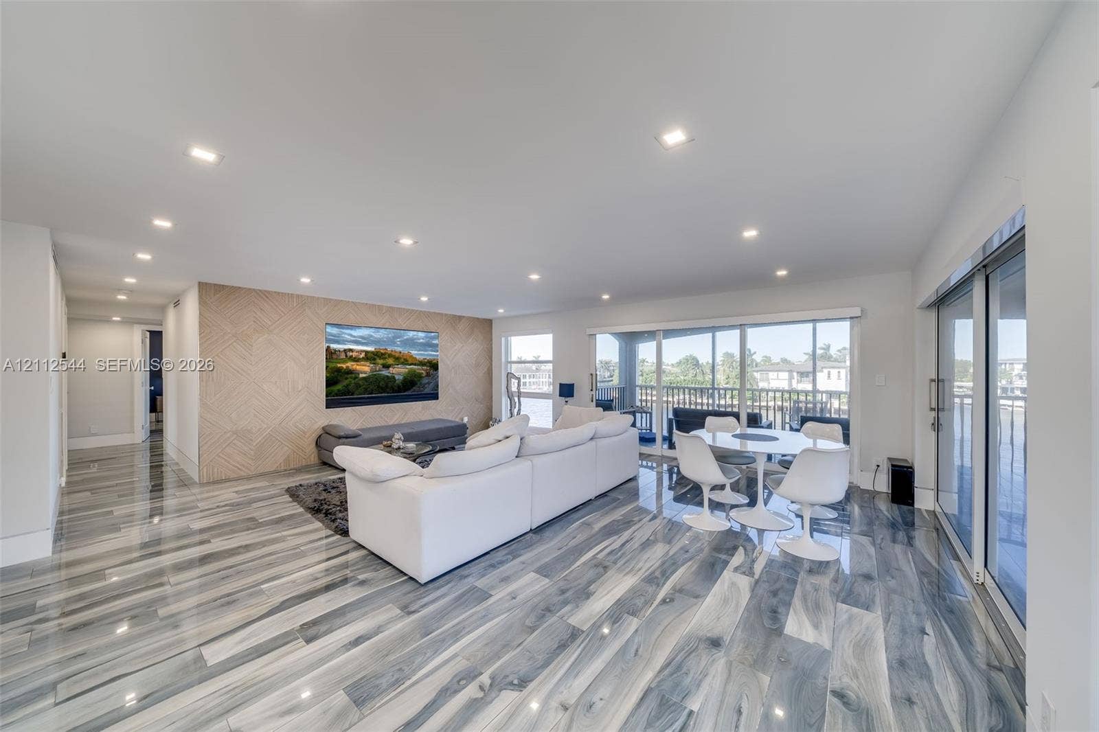 2871 N Ocean Boulevard, #R360, Boca Raton, Boca Raton, FL 33431 Open-concept room featuring polished stone-finish flooring, recessed lighting, a geometric wood-paneled accent wall, and floor-to-ceiling glass sliding doors