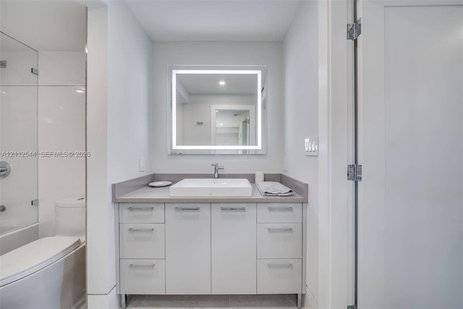 2871 N Ocean Boulevard, #R360, Boca Raton, Boca Raton, FL 33431 Bathroom vanity featuring flat-panel cabinetry, a rectangular vessel sink, solid-surface countertop, and an integrated LED-backlit mirror