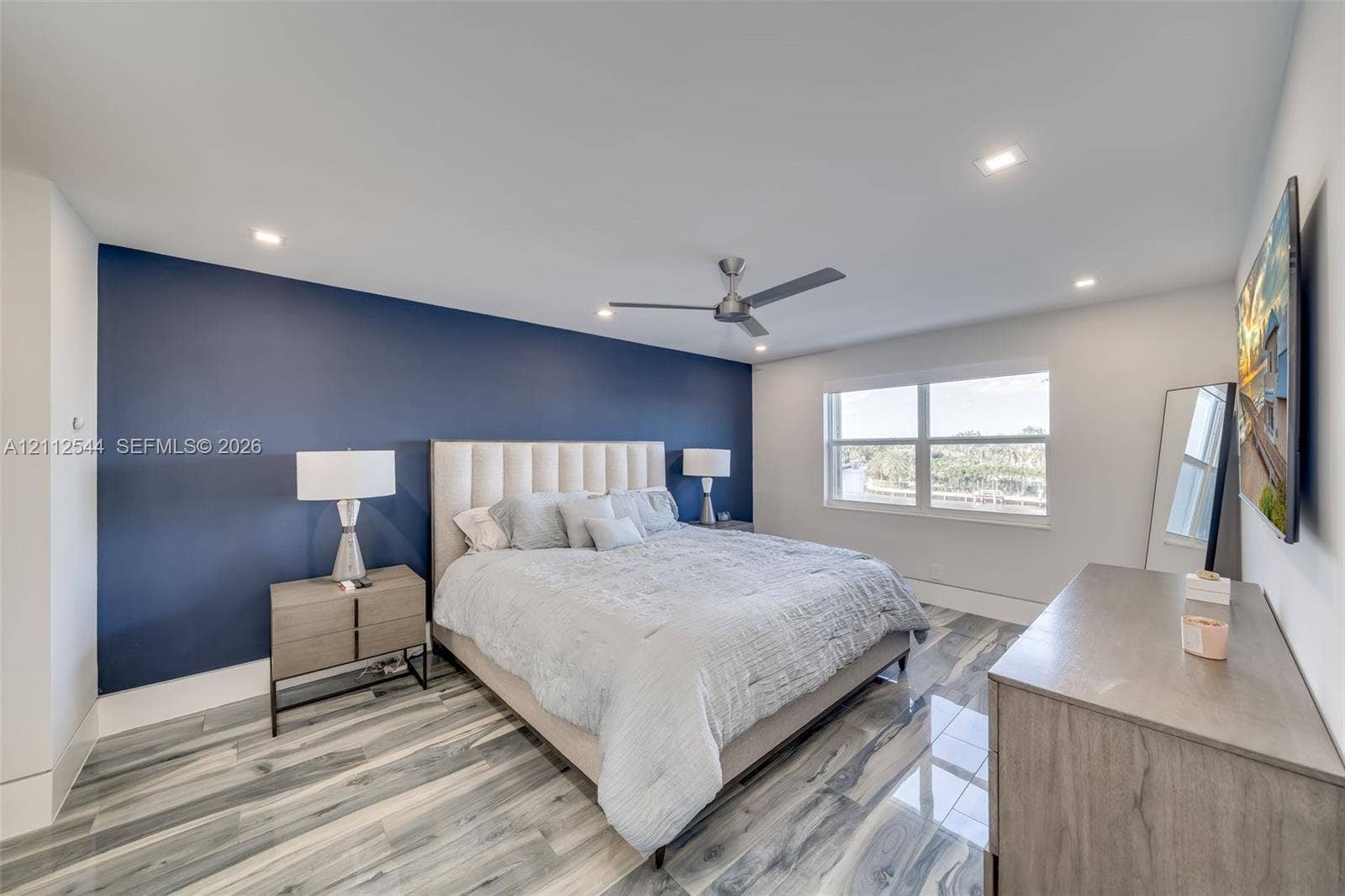 2871 N Ocean Boulevard, #R360, Boca Raton, Boca Raton, FL 33431 Bedroom featuring a bold navy accent wall, wood-finish tile flooring, recessed ceiling lighting, and a modern brushed-metal ceiling fan