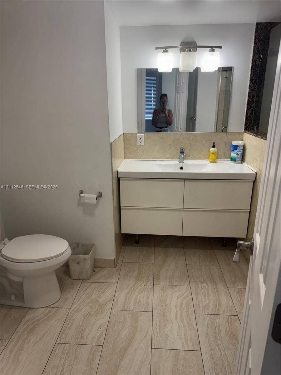 1301 NE Miami Gardens Drive, #515W, Miami, Miami, FL 33179 Modern floating vanity with a dual-drawer cabinet, white countertop, and polished chrome faucet, complemented by oversized neutral floor tiling and a three-light fixture