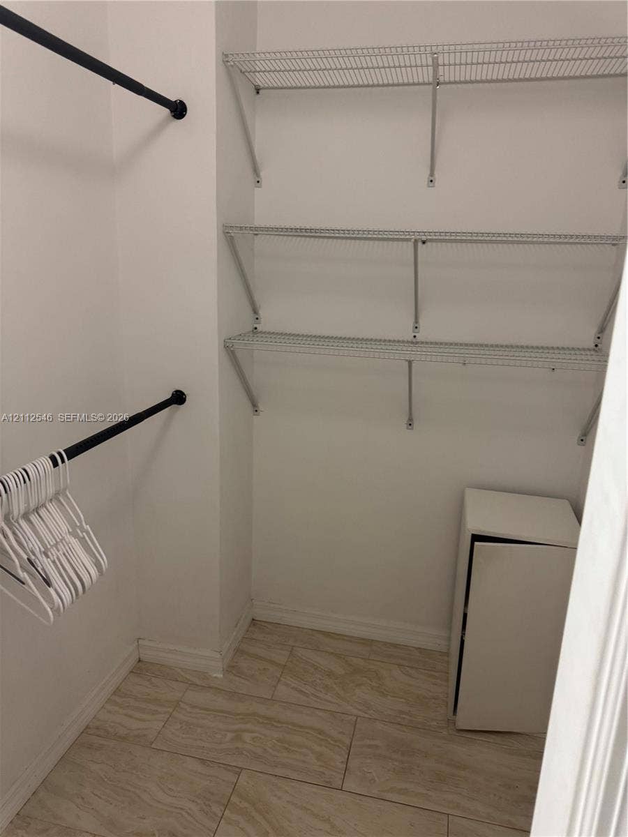 1301 NE Miami Gardens Drive, #515W, Miami, Miami, FL 33179 Storage area featuring tile flooring, matte black hanging rods, and multi-tier wire shelving