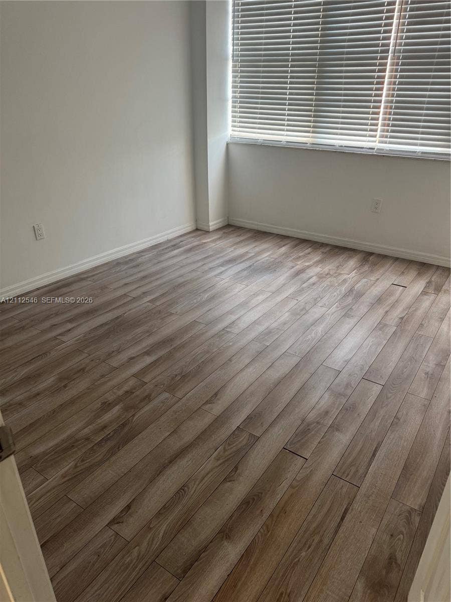 1301 NE Miami Gardens Drive, #515W, Miami, Miami, FL 33179 Room featuring wood-finish flooring and a large window equipped with horizontal blinds