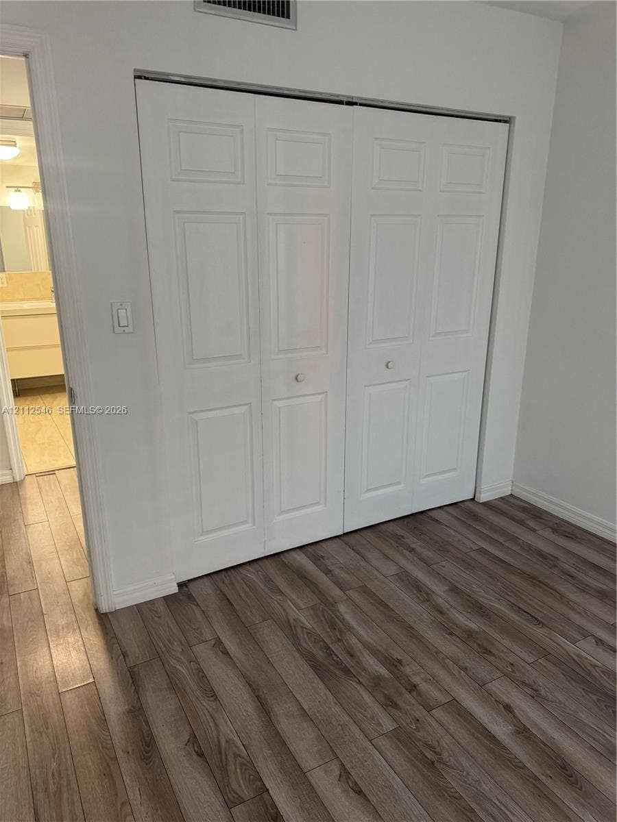1301 NE Miami Gardens Drive, #515W, Miami, Miami, FL 33179 Bi-fold closet doors with white raised-panel detailing and wood-finish flooring