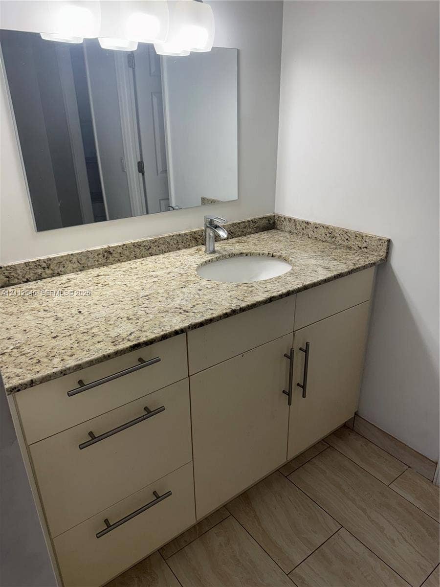 1301 NE Miami Gardens Drive, #515W, Miami, Miami, FL 33179 Vanity featuring stone-finish countertop, undermount sink, brushed metal hardware, and wood-finish tile flooring