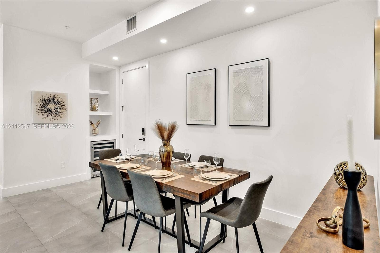 Large-format tile flooring, recessed ceiling lighting, and built-in shelving featuring an integrated wine refrigerator