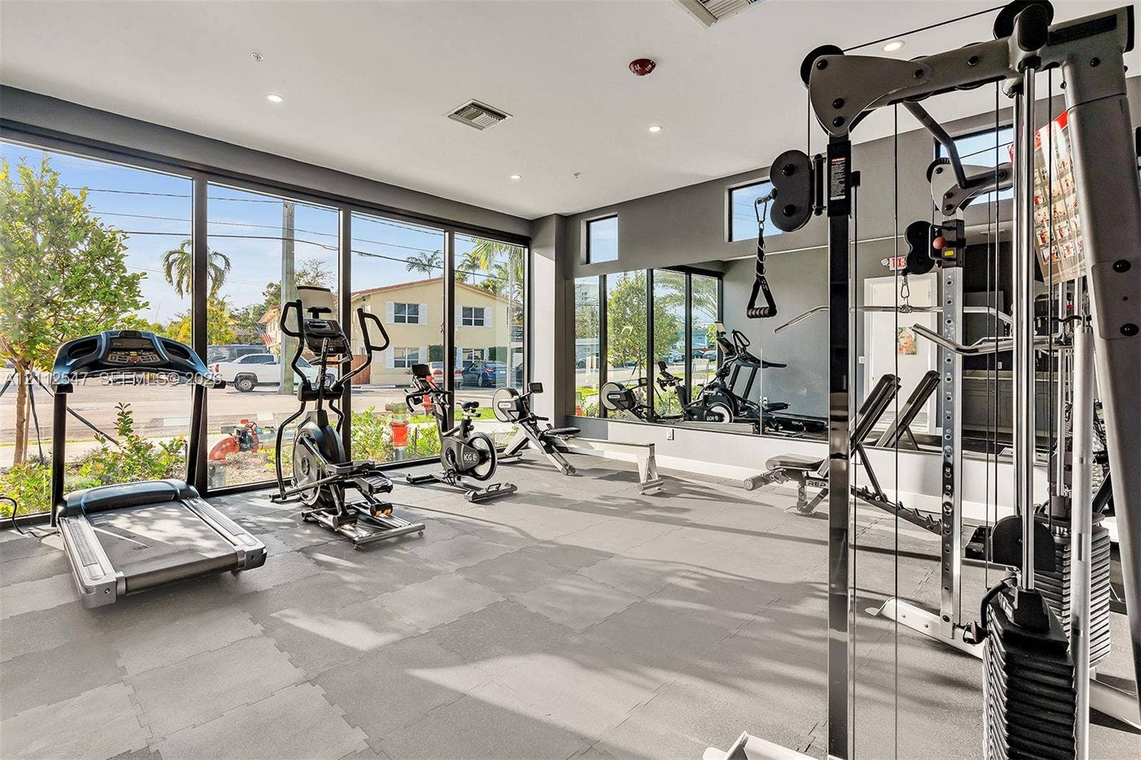 Fitness center featuring floor-to-ceiling windows, full-wall mirrors, recessed lighting, and rubberized modular flooring