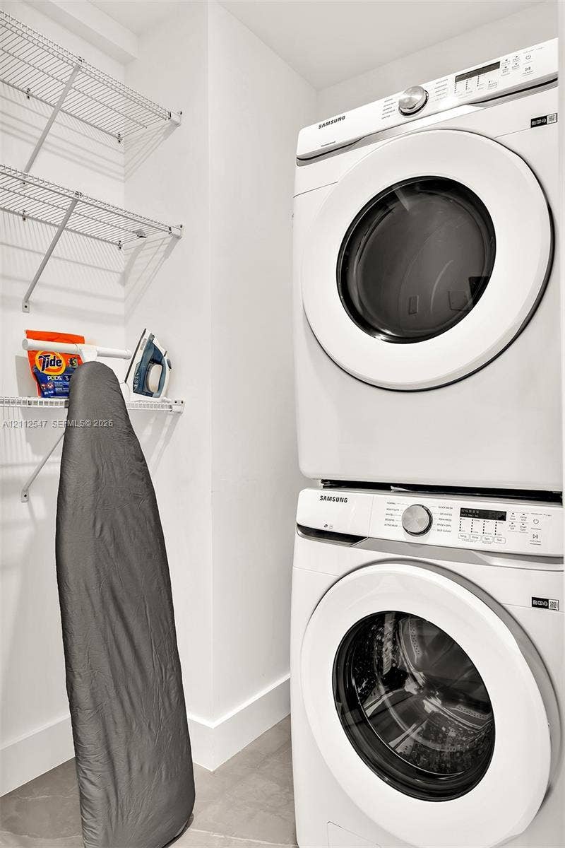 Laundry area featuring a stacked front-loading washer and dryer with integrated white wire shelving
