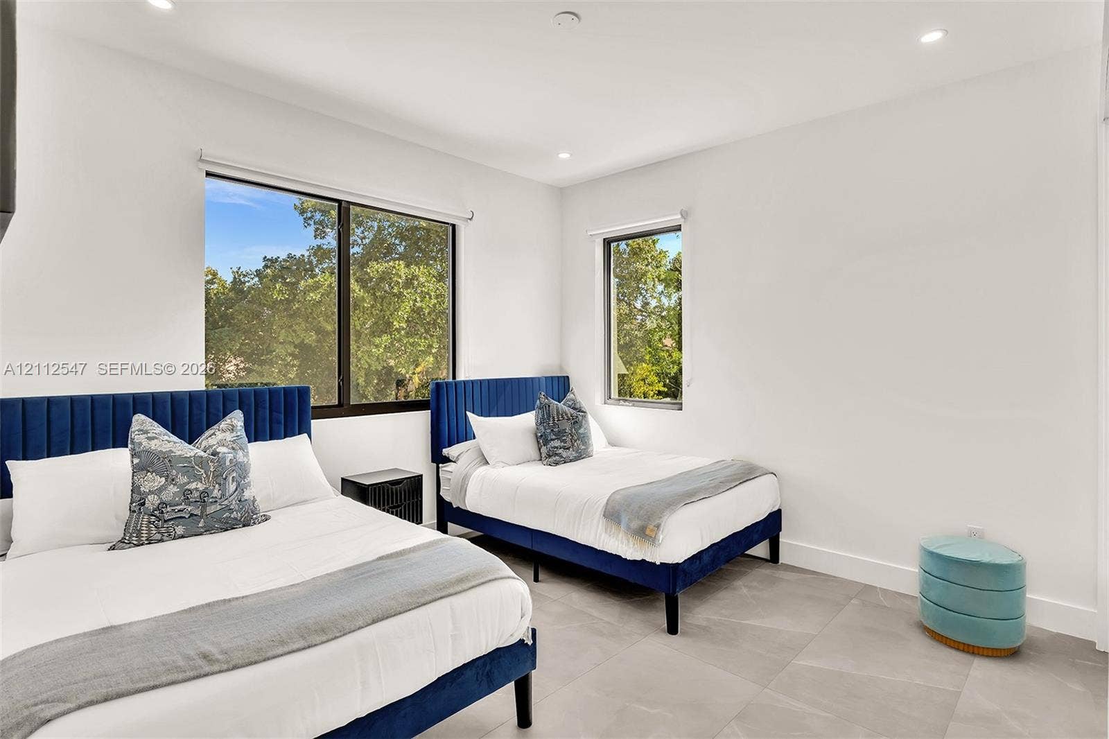 Neutral-toned tile flooring, recessed ceiling lighting, and large-format dual windows with exterior foliage