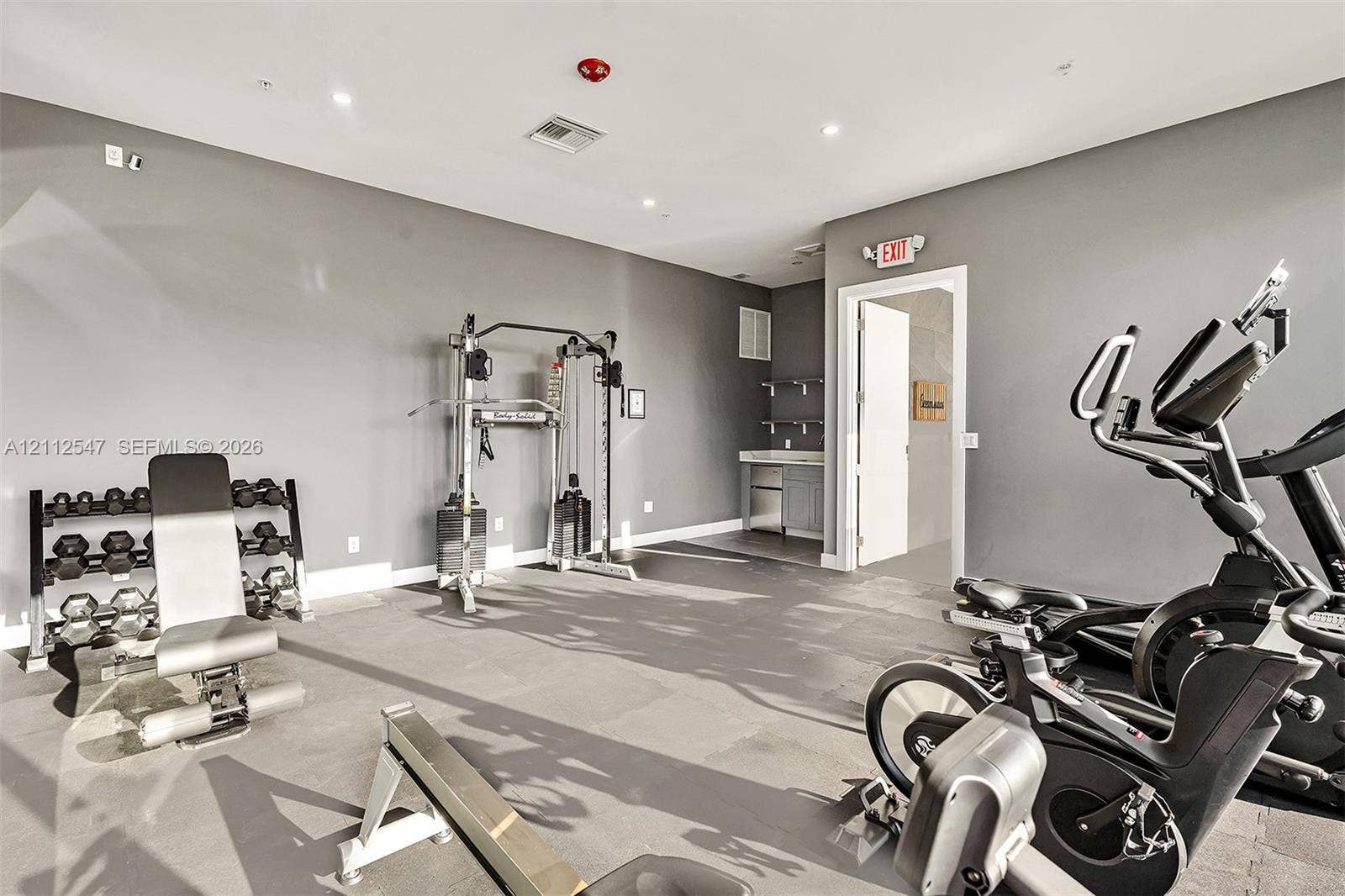 Fitness room featuring rubberized flooring, recessed lighting, and a built-in cabinetry unit with a countertop