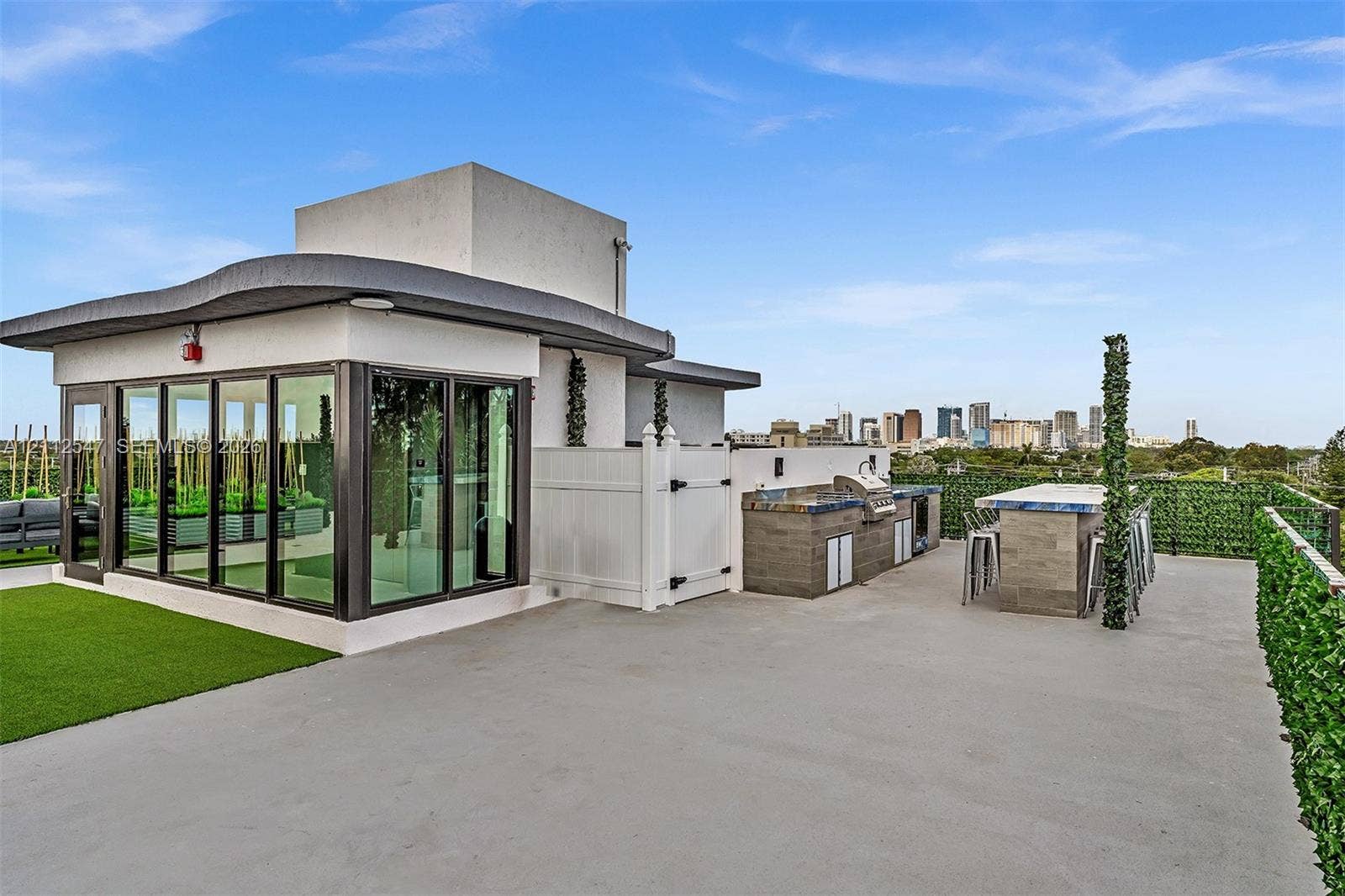 Rooftop terrace featuring concrete flooring, a built-in outdoor kitchen with a stainless steel grill, a stone-finish bar, and a glass-enclosed structure