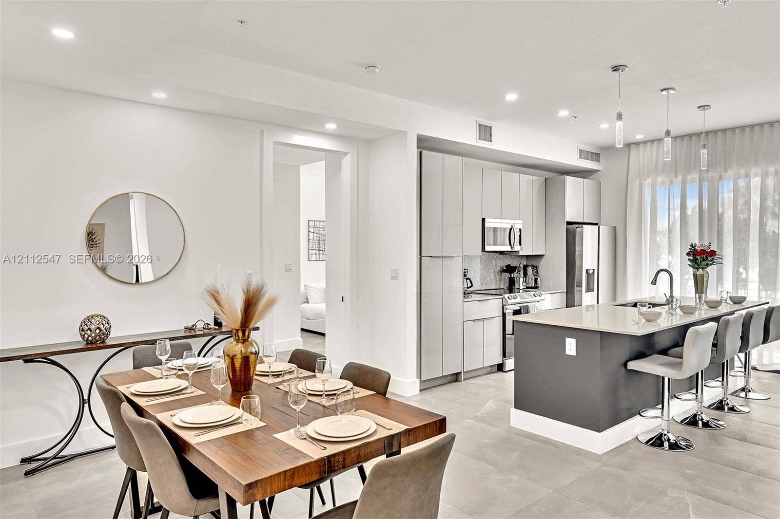Kitchen featuring slab-front cabinetry, a quartz-topped center island with bar seating, stainless steel appliances, recessed lighting, and large-format tile flooring