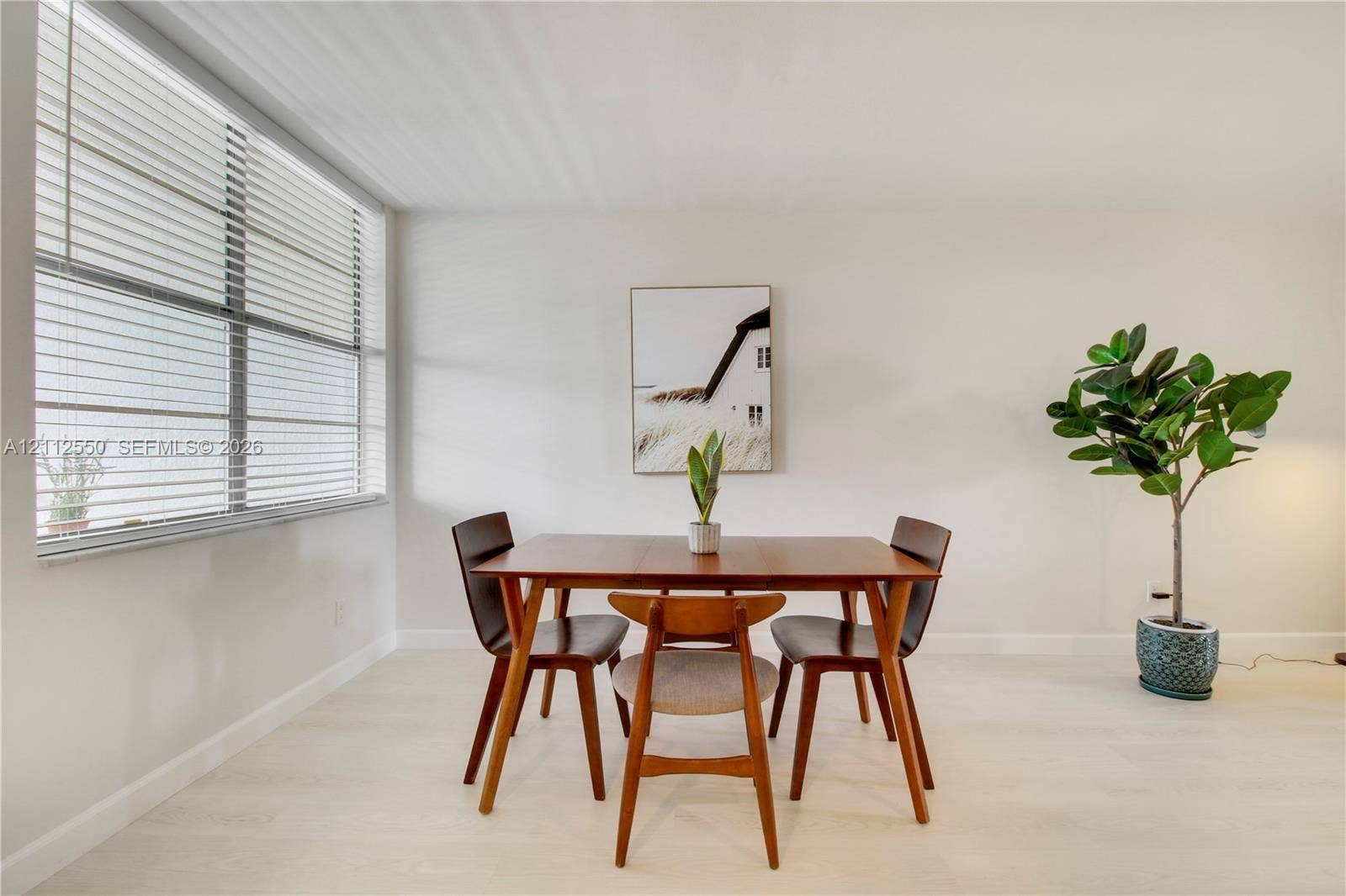 Neutral wall palette with wood-finish flooring and large-scale window featuring adjustable horizontal blinds