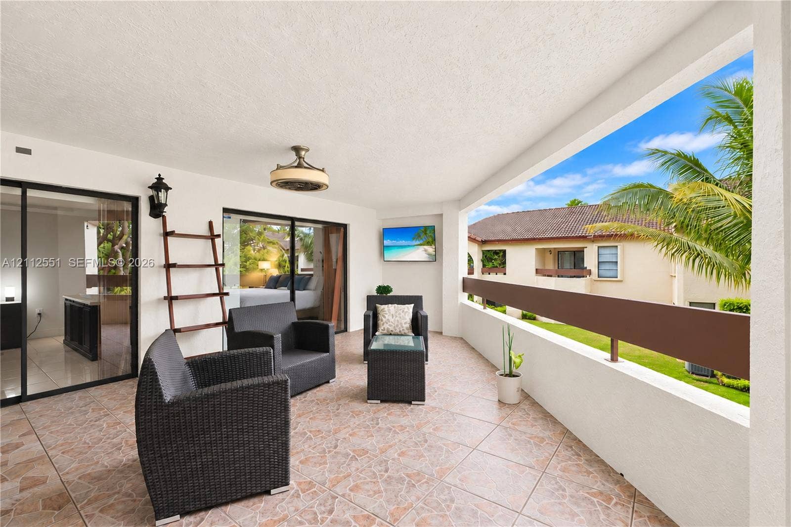 Covered balcony featuring tile flooring, a wall-mounted light fixture, a ceiling fan with integrated lighting, and a horizontal railing