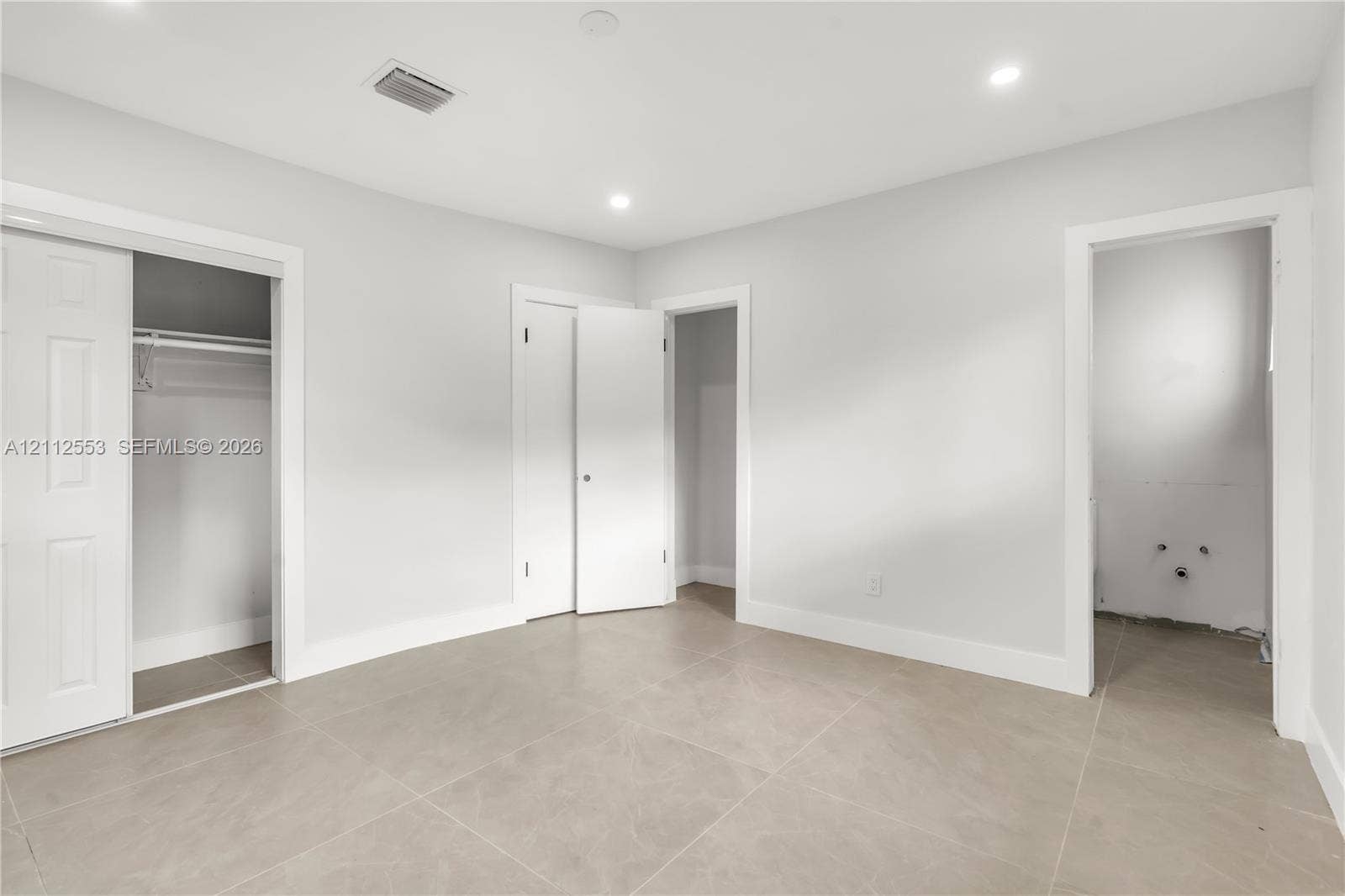 Neutral-toned ceramic tile flooring, recessed ceiling lighting, and multiple interior closets with white paneled doors