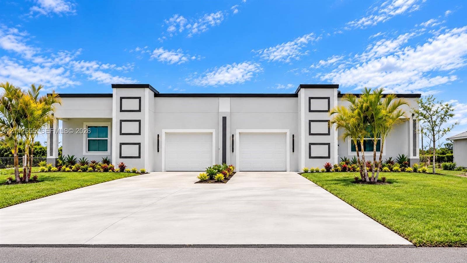 1105/1107 S Gilbert Avenue, Lehigh Acres, FL 33973 Contemporary exterior featuring a flat roofline, dual-garage configuration, concrete driveway, and minimalist architectural trim