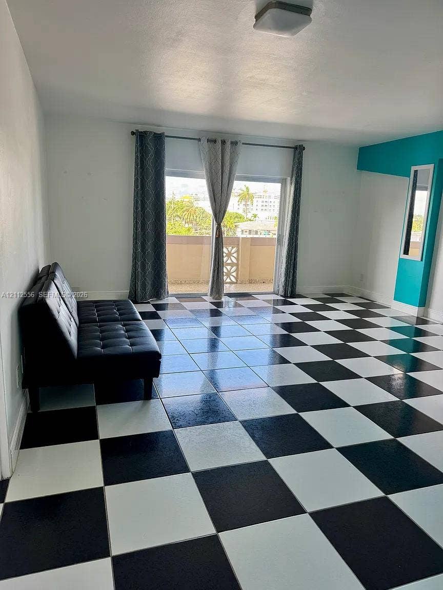 8400 Byron Avenue, #4E, Miami Beach, Miami Beach, FL 33141 Black and white checkerboard tile flooring, sliding glass door, and a built-in vertical accent wall with a recessed mirror
