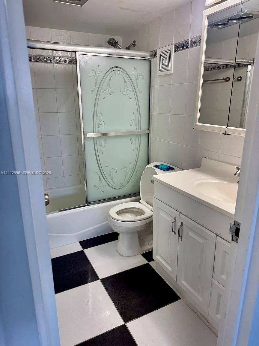8400 Byron Avenue, #4E, Miami Beach, Miami Beach, FL 33141 Bathroom featuring a vanity with integrated sink, glass-enclosed shower and tub combination, decorative tile backsplash, and high-contrast checkered flooring