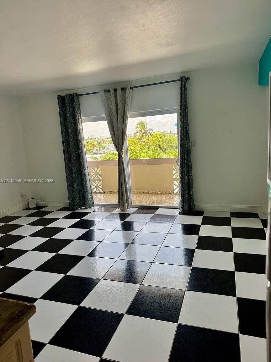 8400 Byron Avenue, #4E, Miami Beach, Miami Beach, FL 33141 Room featuring a black and white checkerboard tile floor and a sliding glass door with access to a balcony with decorative screen block railings