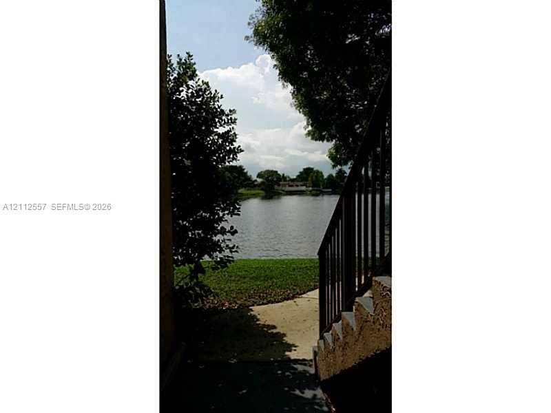 2121 NW 96th Terrace, #14J, Pembroke Pines, Pembroke Pines, FL 33024 Exterior staircase with metal railings leading to a waterfront lot featuring a grass lawn and mature trees