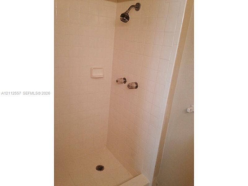 2121 NW 96th Terrace, #14J, Pembroke Pines, Pembroke Pines, FL 33024 Shower enclosure featuring white square wall tile, a built-in recessed soap dish, chrome dual-handle plumbing fixtures, and a chrome shower head