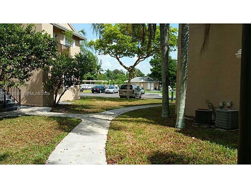 2121 NW 96th Terrace, #14J, Pembroke Pines, Pembroke Pines, FL 33024 Exterior grounds featuring concrete walkways, mature trees, and stucco building facades