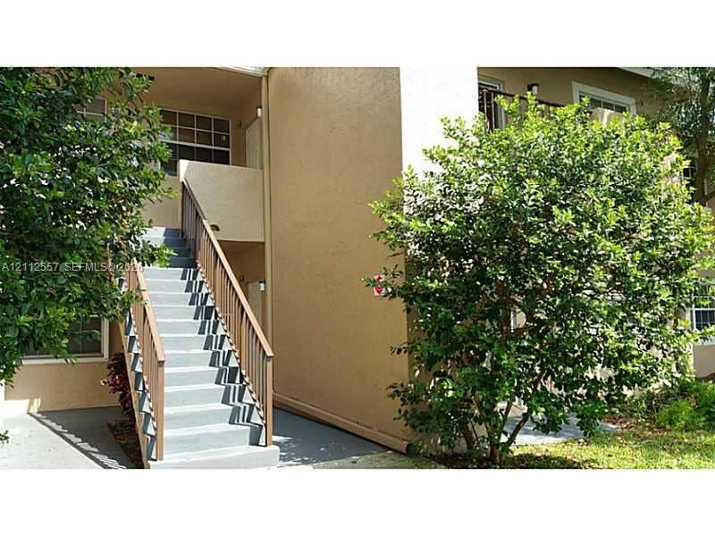 2121 NW 96th Terrace, #14J, Pembroke Pines, Pembroke Pines, FL 33024 Exterior staircase with wooden railings featuring concrete steps and stucco siding