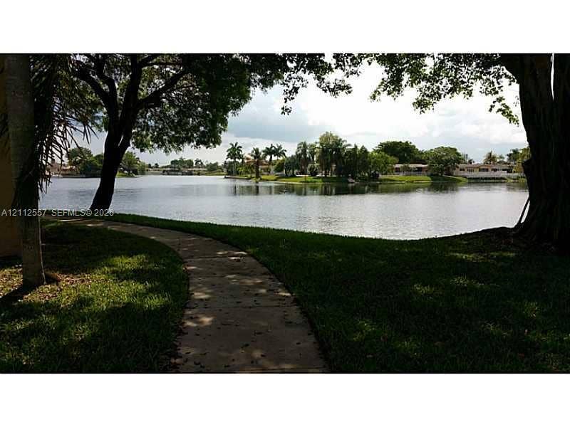 2121 NW 96th Terrace, #14J, Pembroke Pines, Pembroke Pines, FL 33024 Waterfront grounds featuring a concrete walking path, mature trees, manicured turf, and open water scenery