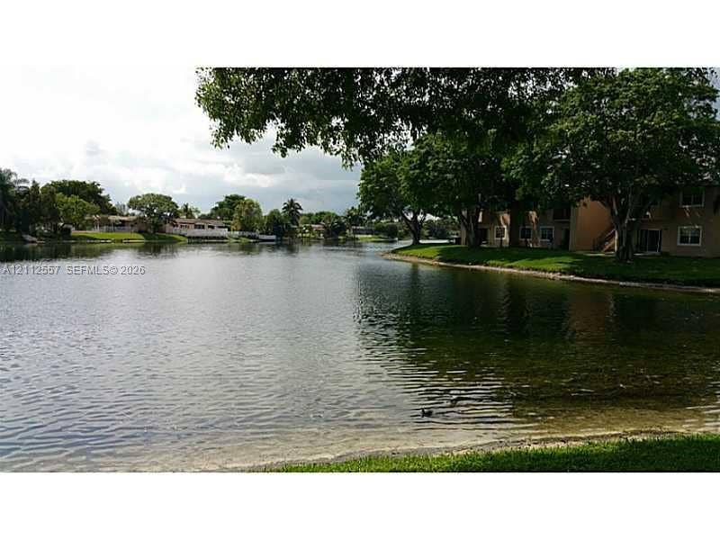 2121 NW 96th Terrace, #14J, Pembroke Pines, Pembroke Pines, FL 33024 Waterfront property featuring expansive lake frontage, mature shade trees, and manicured green space