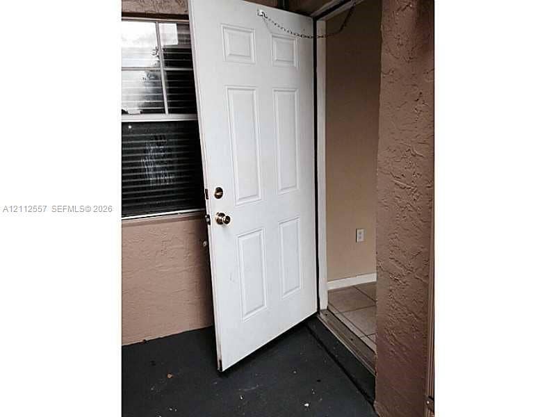 2121 NW 96th Terrace, #14J, Pembroke Pines, Pembroke Pines, FL 33024 White six-panel entry door with metallic hardware, exterior stucco finish, and window featuring horizontal blinds