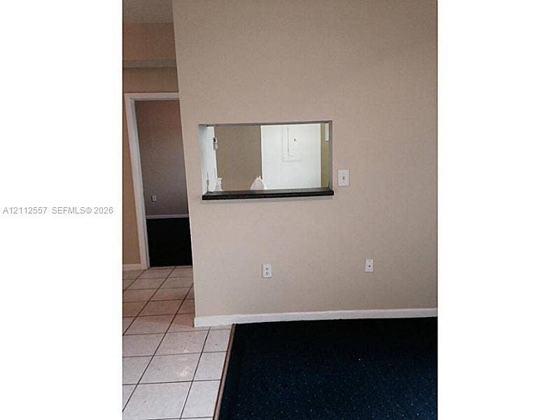2121 NW 96th Terrace, #14J, Pembroke Pines, Pembroke Pines, FL 33024 Interior wall featuring a pass-through opening with a dark-toned ledge, white ceramic floor tiling, and dark-toned flooring