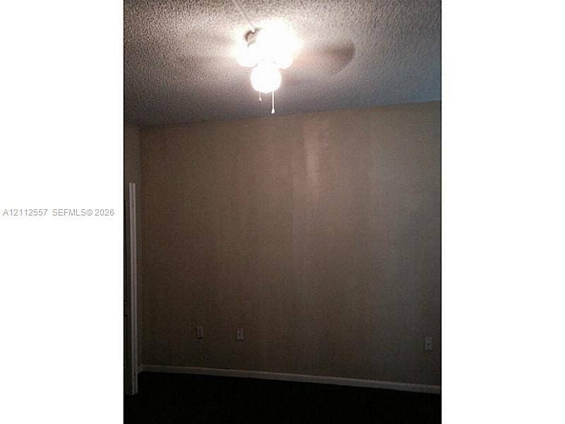 2121 NW 96th Terrace, #14J, Pembroke Pines, Pembroke Pines, FL 33024 Room featuring a ceiling-mounted light fixture with a three-blade fan, textured ceiling, and doorway entrance