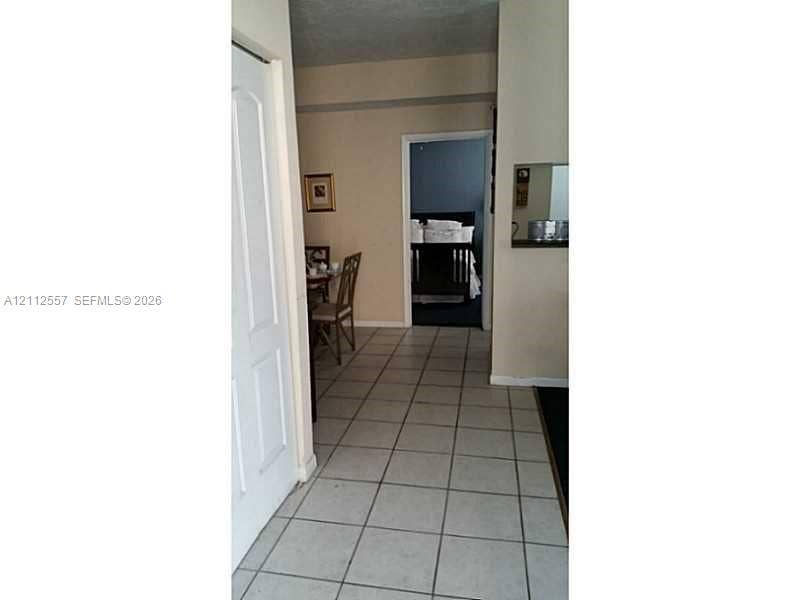 2121 NW 96th Terrace, #14J, Pembroke Pines, Pembroke Pines, FL 33024 Neutral-toned interior featuring ceramic tile flooring, a recessed wall-mounted mirror, and a multi-panel door