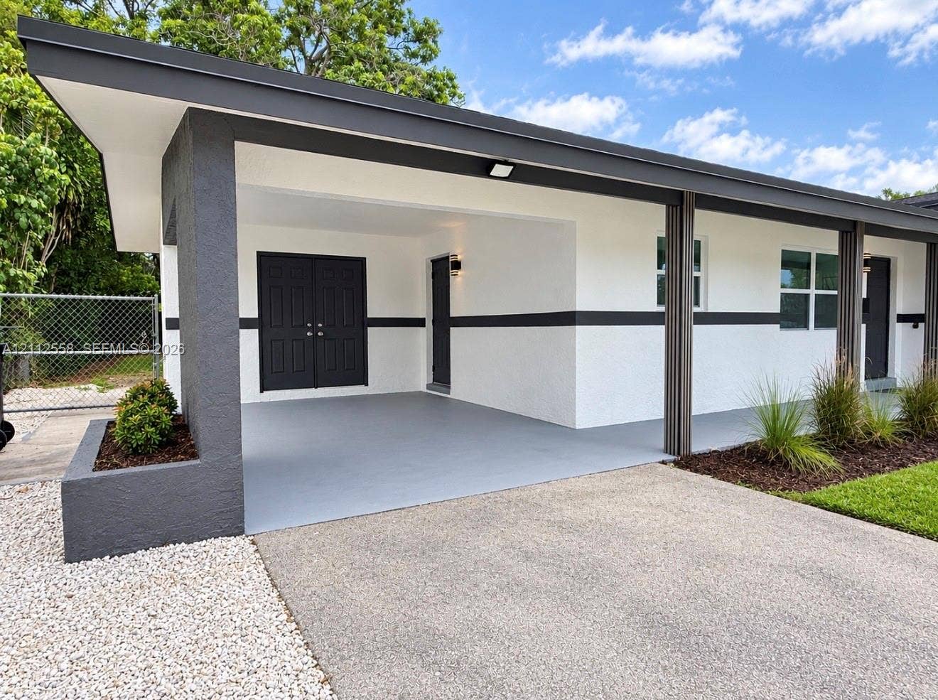 Modern exterior featuring a covered carport with painted concrete flooring, double entry doors, a built-in masonry planter, and recessed lighting