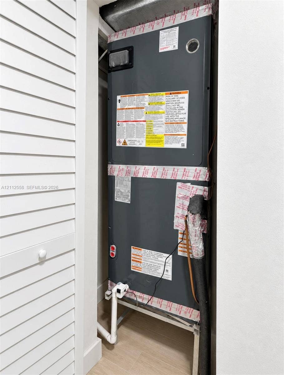 Dedicated utility closet featuring an enclosed heating and cooling air handler unit and louvered bifold doors