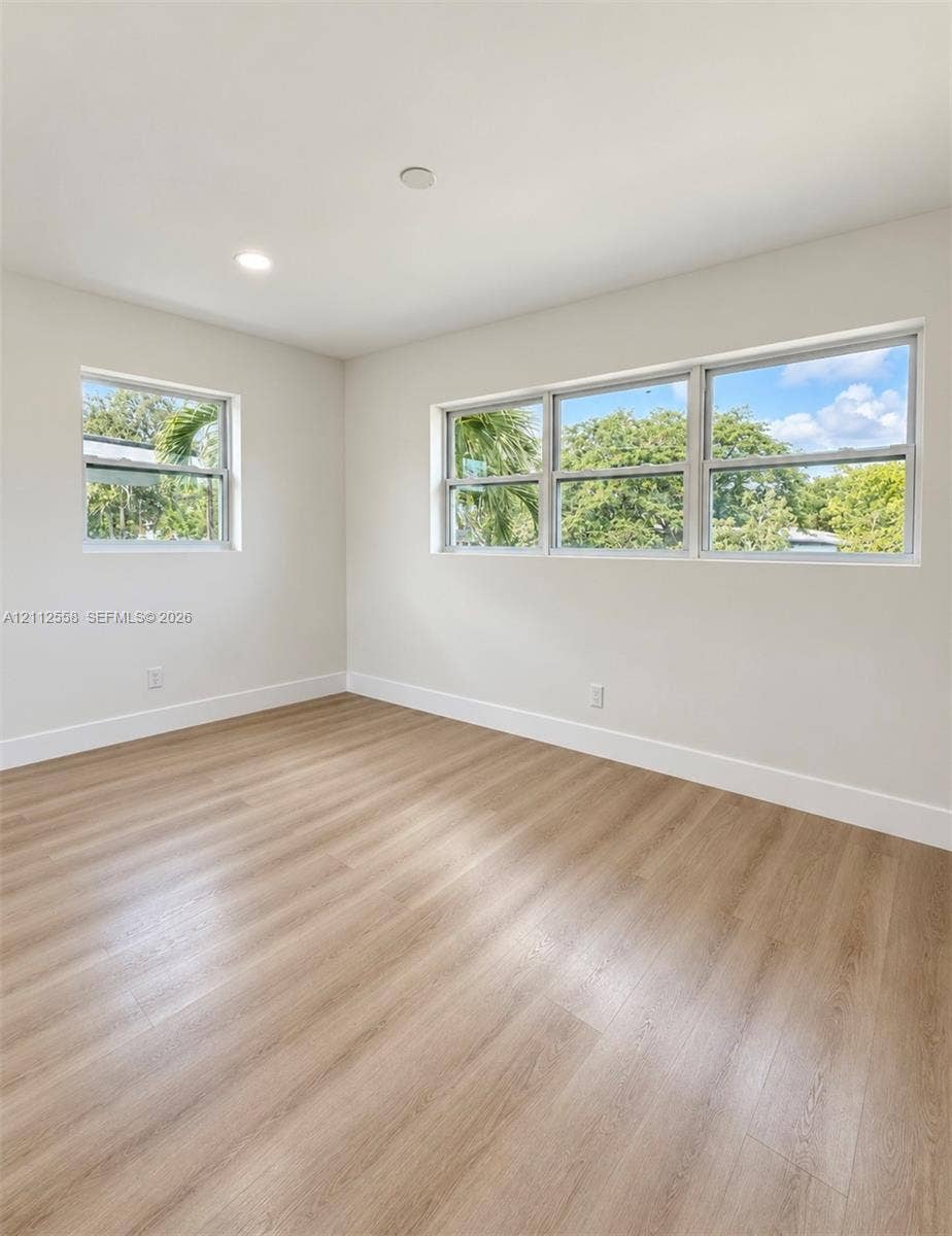 Neutral interior featuring wood-finish flooring, recessed lighting, and multiple windows with light-filtering frames