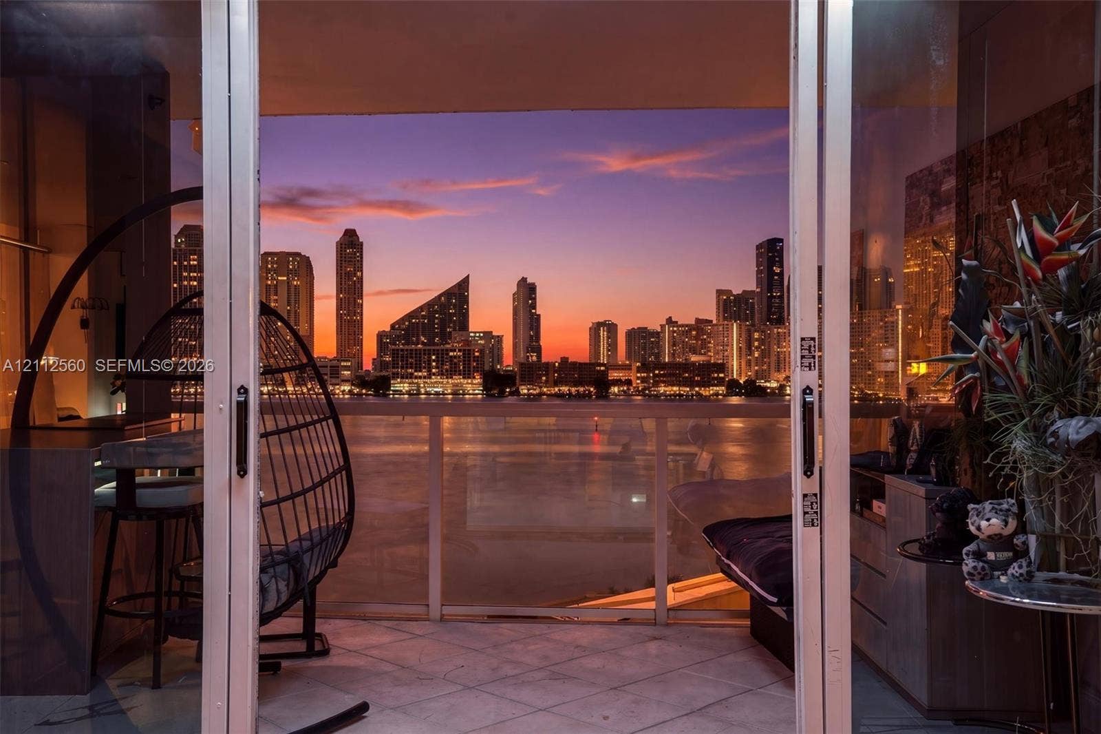 4000 Island Boulevard, #701, Aventura, FL 33160 Covered balcony featuring tile flooring and a glass-paneled railing, with expansive waterfront and cityscape scenery