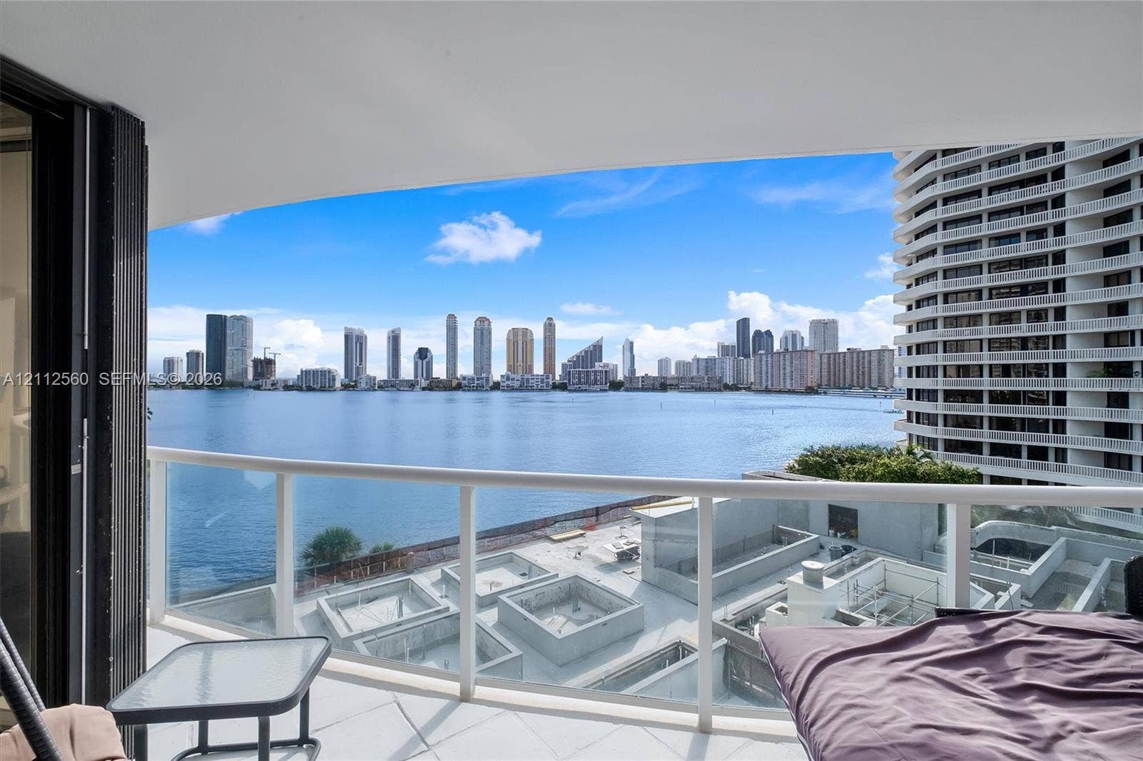 4000 Island Boulevard, #701, Aventura, FL 33160 Private balcony featuring a glass-panel railing and tile flooring, oriented toward a water and city skyline backdrop