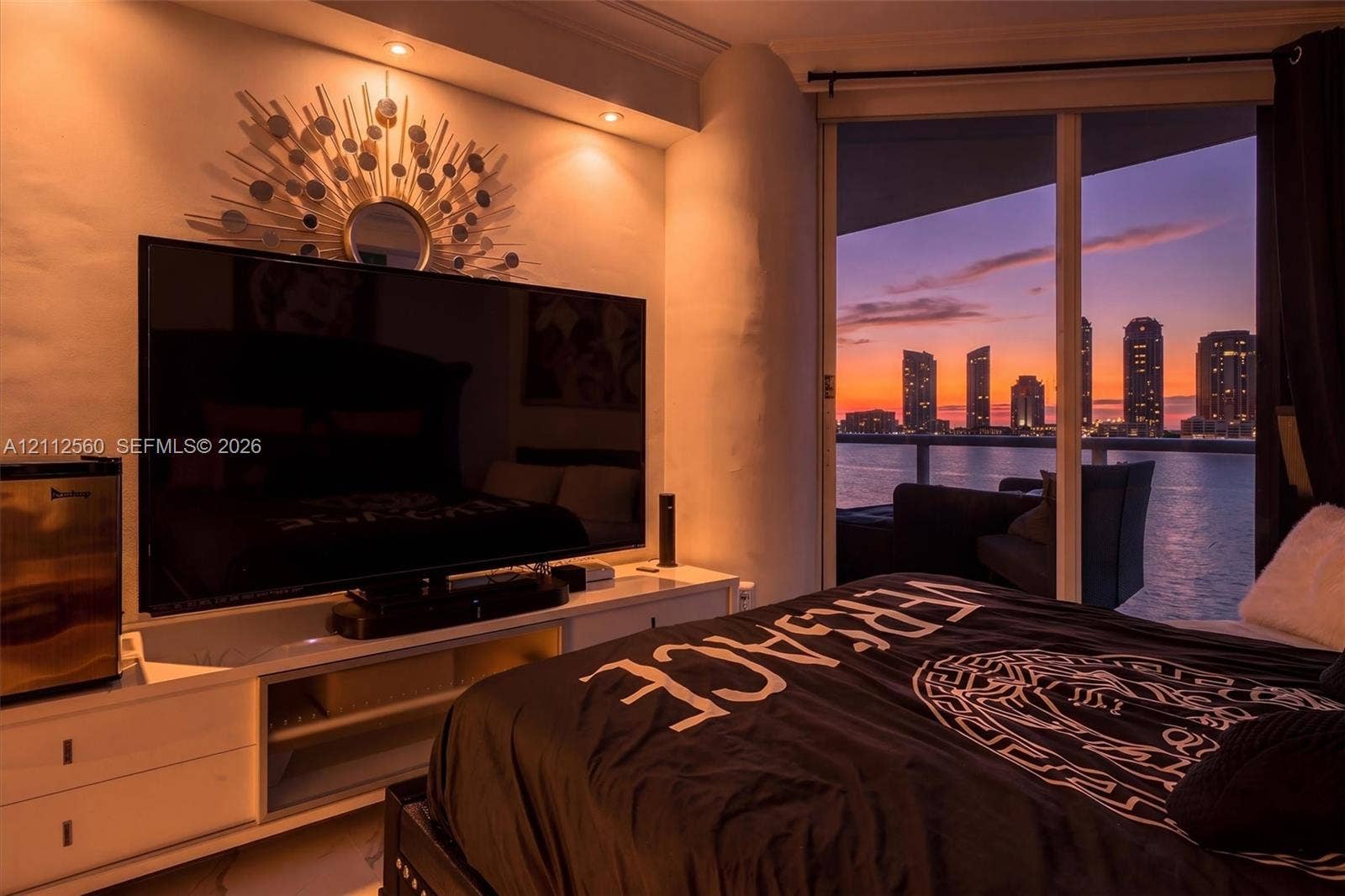 4000 Island Boulevard, #701, Aventura, FL 33160 Floor-to-ceiling glass sliding doors, built-in recessed ceiling lighting, and private balcony with metal railing, set against a waterfront city skyline backdrop