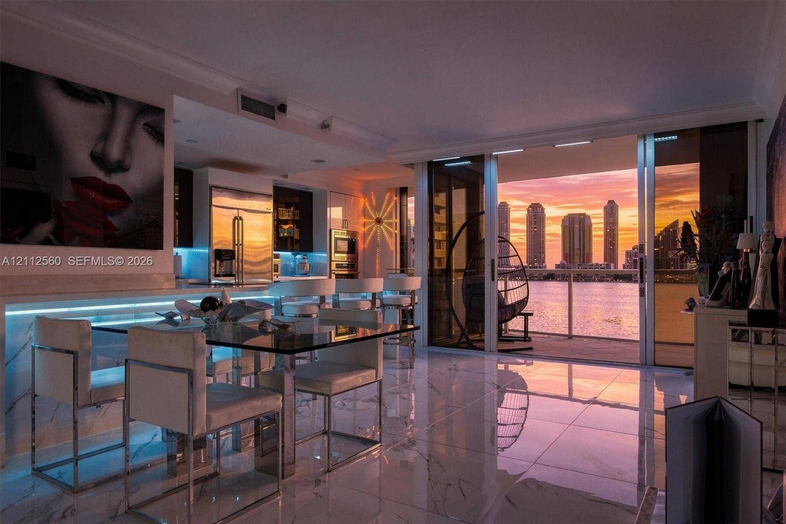 4000 Island Boulevard, #701, Aventura, FL 33160 Large-format polished tile flooring, integrated linear LED under-cabinet lighting, stainless steel built-in appliances, and expansive sliding glass doors opening to a balcony with waterfront and skyline scenery